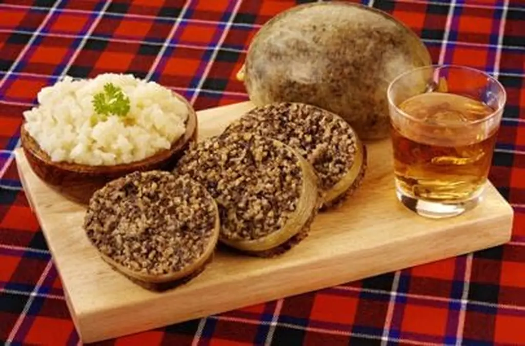 Haggis with mashed turnip and a glass of whisky on a tartan cloth.