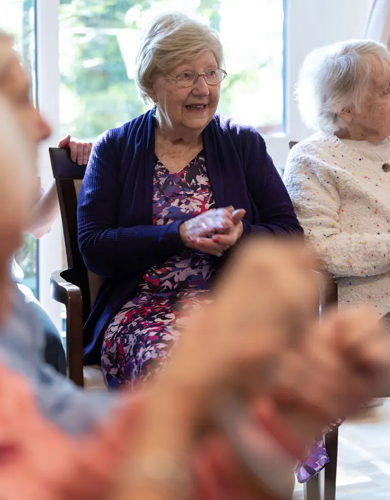 A resident clapping along, in company, at Aria Care Home